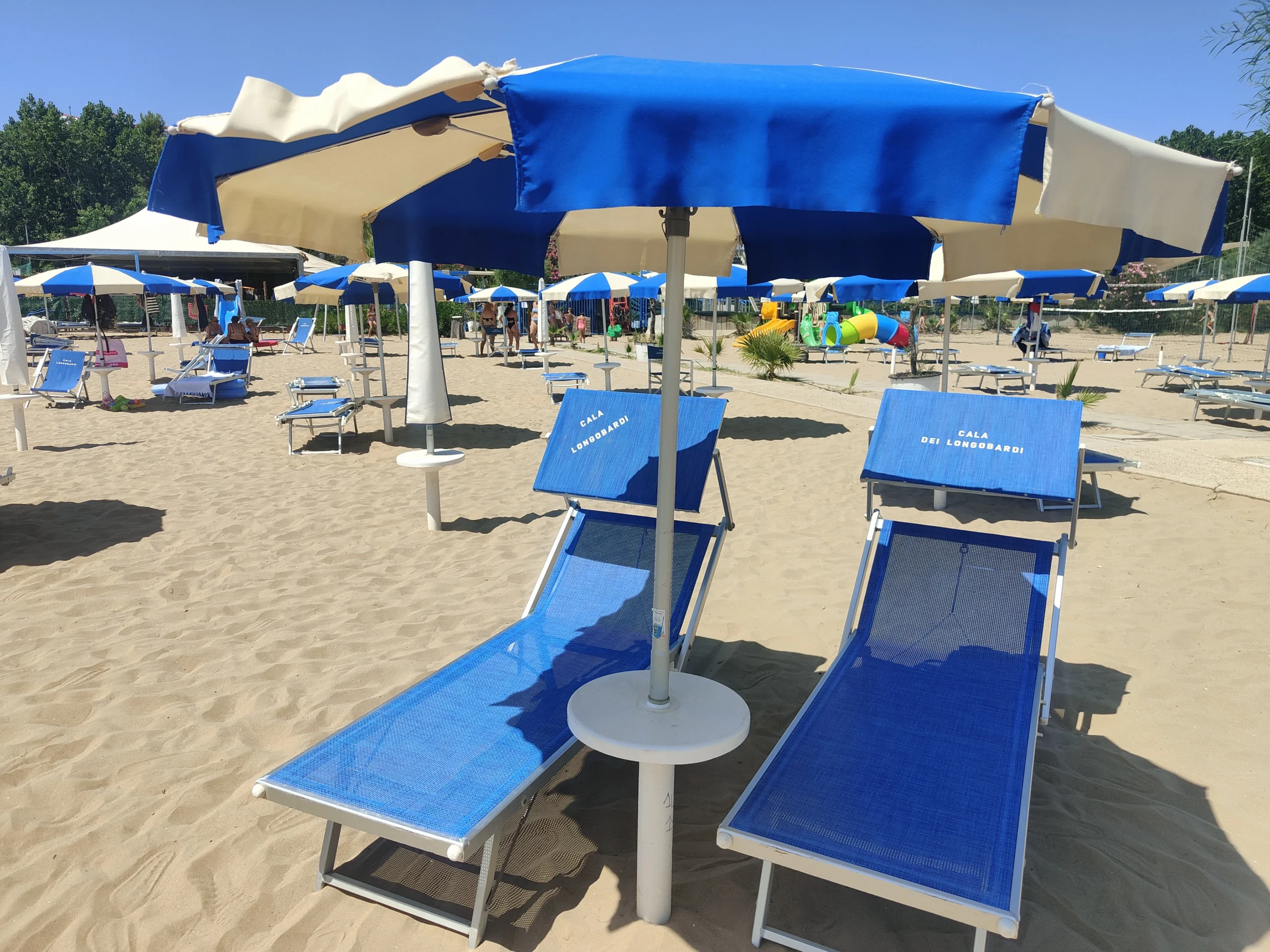 Lettini blu e ombrelloni su spiaggia dorata al Lido Cala dei Longobardi a Termoli